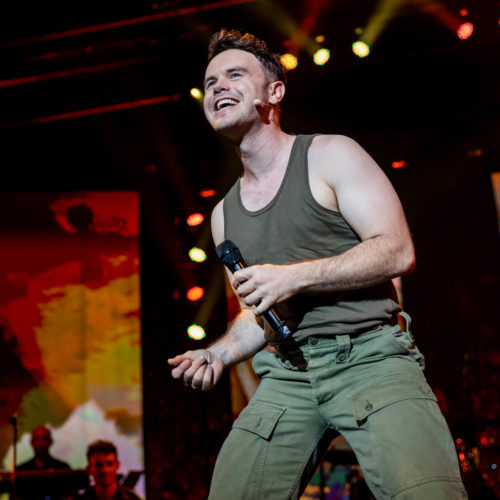 Male vocalist smiling as he performs in military-style costume